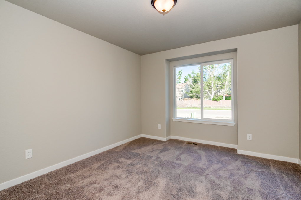 A long shot of the brown carpet and sliding window in the room