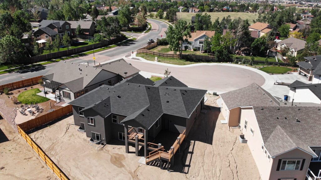 A drone shot of the Grey colored house with metal roofing and fencing